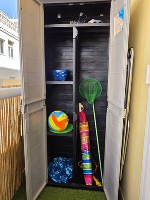 A compact storage unit with shelves, a hanging net, and a ball.