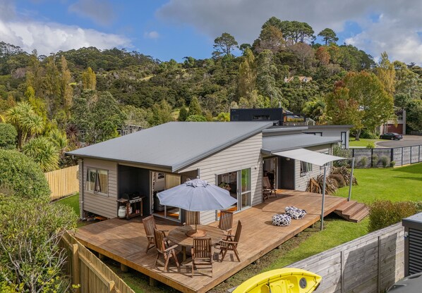 A modern house with a deck, outdoor furniture, and a yellow boat.