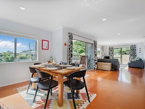 A modern dining area with a wooden table, black chairs, and a colorful rug.