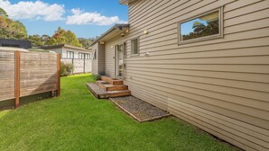 A single-story house with a small front yard and a wooden deck. - Flaxmill Haven - Cooks Beach Holiday Home (Whitianga)