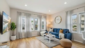 Una sala de estar moderna con un sofá azul, una mesa de centro blanca y un reloj grande en la pared.