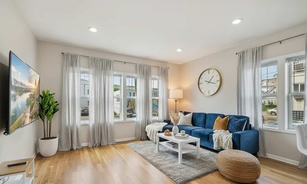 Una sala de estar moderna con un sofá azul, una mesa de centro blanca y un reloj grande en la pared.
