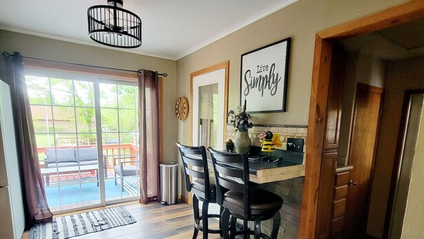 Een eetgedeelte met een houten tafel en stoelen, een kroonluchter en een bord met de tekst 'Live Simply' aan de muur.