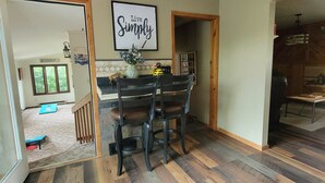 Een eethoek met een houten tafel en stoelen, een hanglamp en een bord met de tekst 'Live Simply' aan de muur.