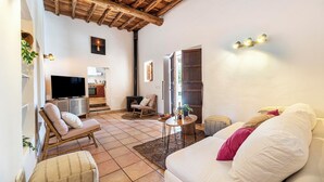 A cozy living room with a wooden ceiling, a sofa, a chair, a small table, and a television. - New! Villa Can Cardona (Santa Agnès de Corona)
