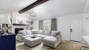 A modern living room with a sectional sofa, a fireplace, and a large window with curtains. - Clean & Comfortble Poker House Near Kalahari! (Round Rock)