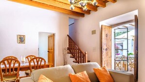 Ein gemütliches Wohnzimmer mit einer Couch, Sesseln, einem Esstisch und einer Treppe.