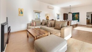 A spacious living room with a sofa set, a wooden coffee table, and a TV.