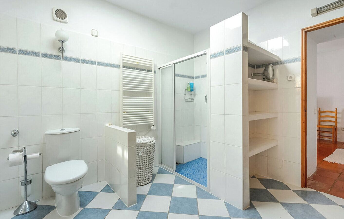 Ein Badezimmer mit Toilette, Dusche, Mülleimer und Ablagefläche für Toilettenartikel.