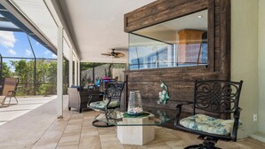 A spacious patio area with a glass-top table, wicker chairs, and a decorative vase. - Watch Dolphins Play From The Patio (Palm Coast)