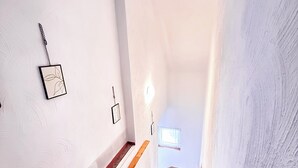 Una escalera con peldaños de madera y paredes blancas.