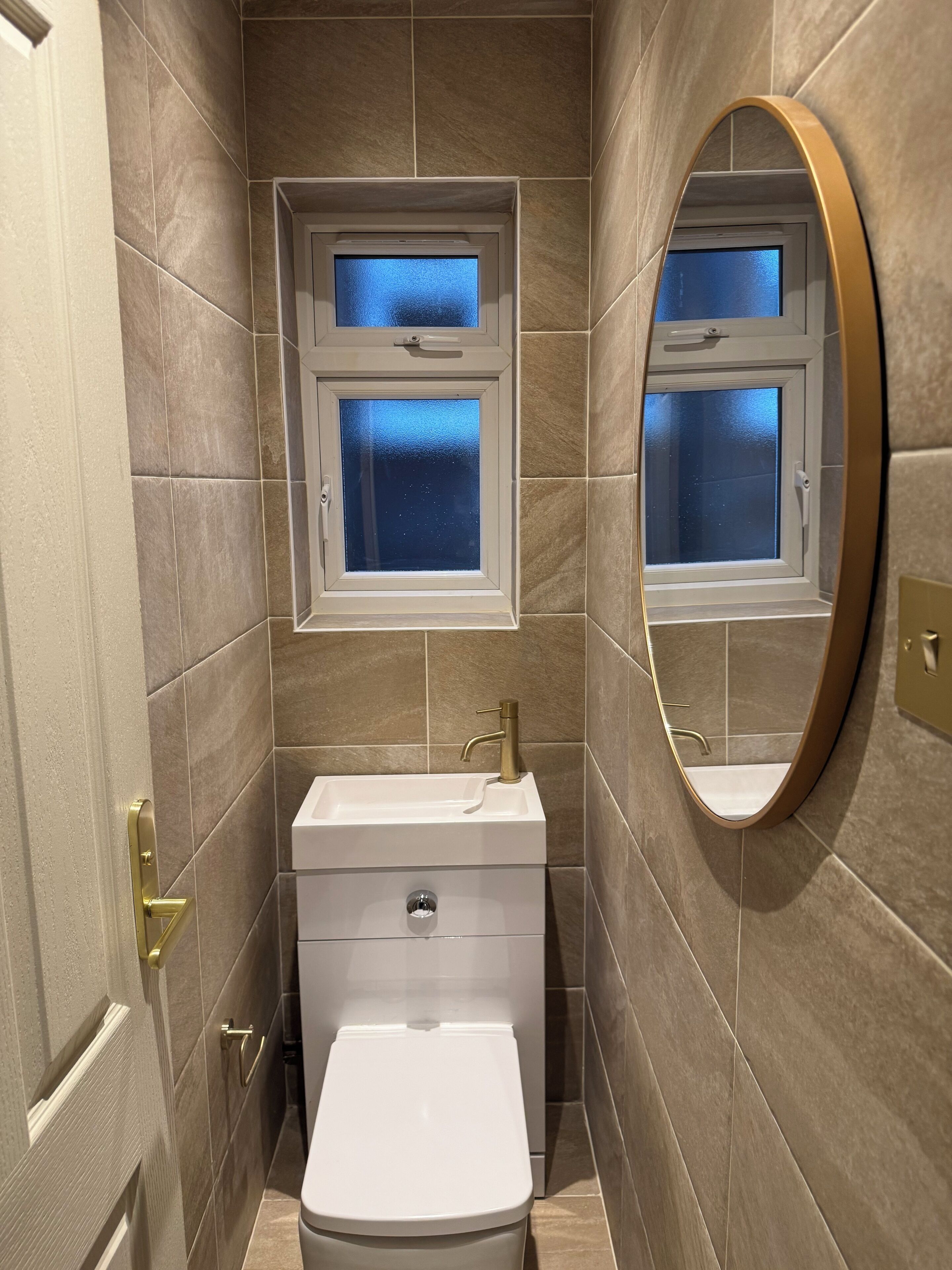 Un baño con inodoro, lavabo y dos ventanas.