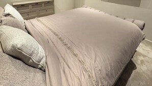 Un dormitori amb un llit gran, un mirall rodó, un televisor fixat a la paret i una porta.
