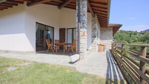 Un edificio de piedra con terraza de madera y valla de madera.