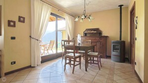 Zona pranzo con tavolo e sedie, un armadietto in legno, un fornello e una vista dalla finestra.