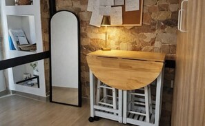 A kitchen with a wooden countertop, a white cabinet, and a stone wall.