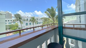A balcony with a wooden railing overlooking a cityscape with palm trees and historic buildings. - Kaira Boutique Hotel (Duong To)