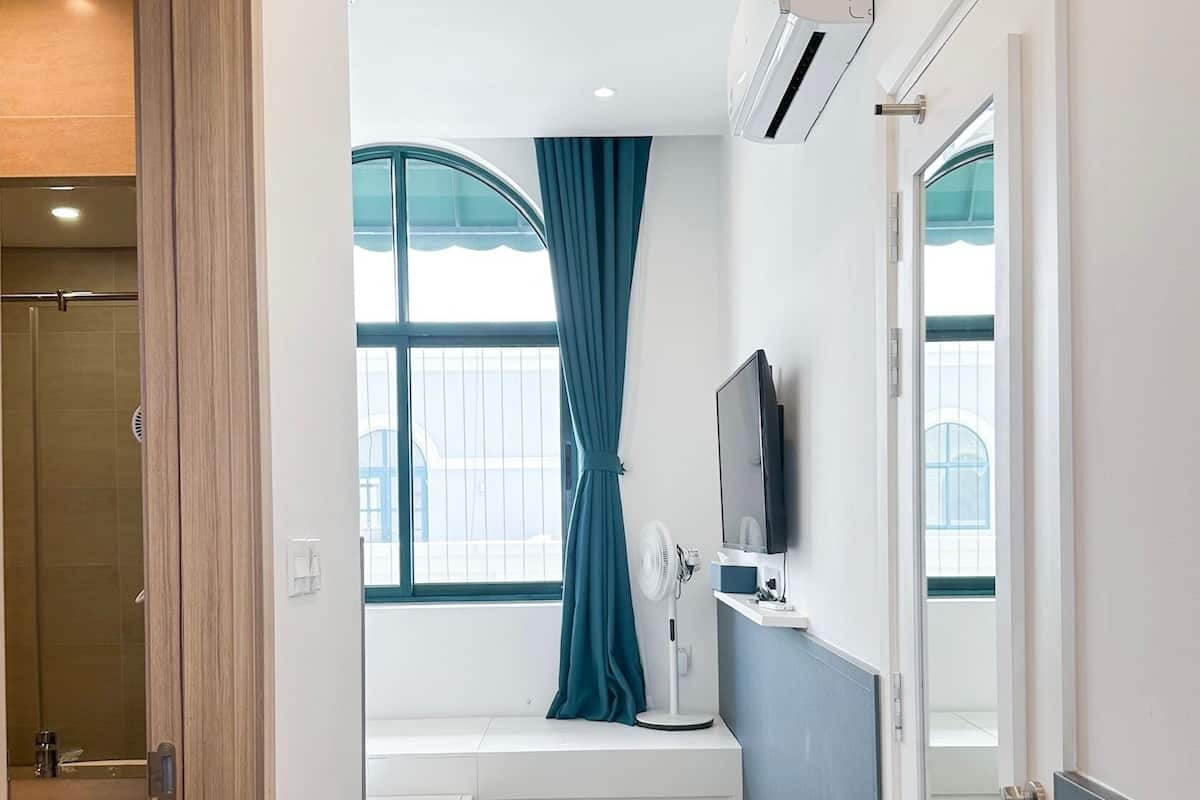 Une salle de bain moderne équipée d’une douche, d’un lavabo, d’un meuble-vasque, d’une fenêtre avec des rideaux et d’un ventilateur fixé au mur.