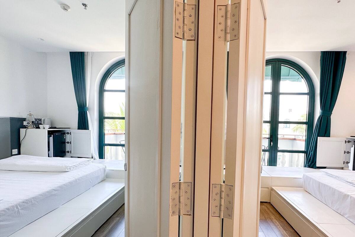 Une chambre d’hôtel avec deux lits, un bureau et une fenêtre.