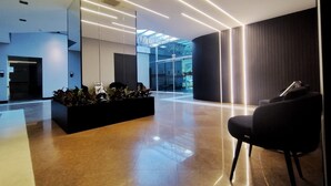 A modern lobby with a glass facade, a reception desk, and a seating area. - Saint Sebastian ap102 - stúdio (Jaragua do Sul)
