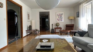 A spacious living room with a large globe, a brown leather chair, a grey sofa, and a wooden coffee table with a map design. - Big house in a secluded area in beautiful Skanör (Skåne län)