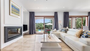 A modern living room with a flat-screen TV, a sofa, a coffee table, and a fireplace. - Villa Bella Vista in Sa Pobla (Sa Pobla)