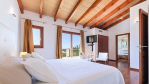 Una habitación de hotel con una cama grande, televisor y balcón con vistas.