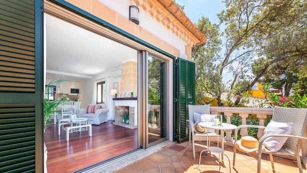 Eine offene Terrasse mit Essbereich, einer Sofagruppe und Blick ins Hausinnere.