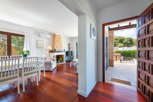 Un salon spacieux doté d’un plancher en bois, de meubles blancs, d’une cheminée et offrant une vue sur l’extérieur.
