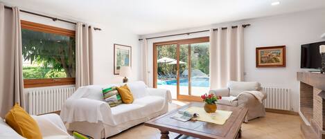 A spacious living room with a large window, a fireplace, and a view of an outdoor pool.