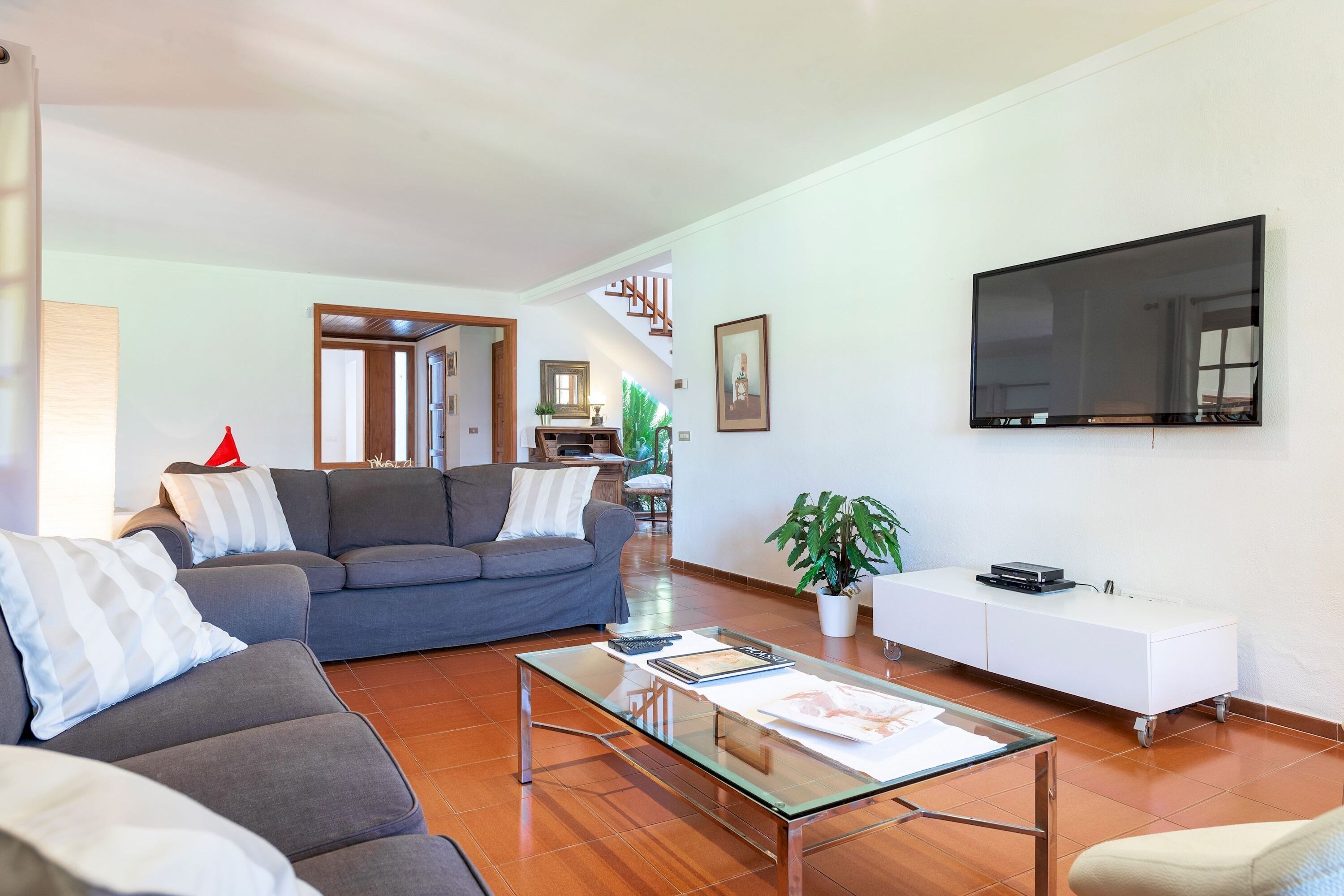 A modern living room with a grey sofa, a glass coffee table, and a white cabinet.