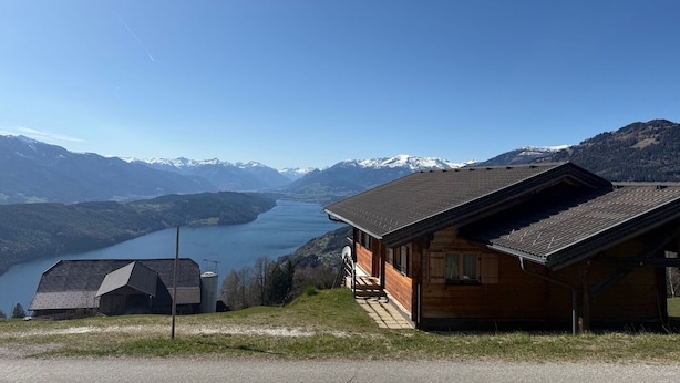 Una cabaña de madera con vista a un lago y montañas.