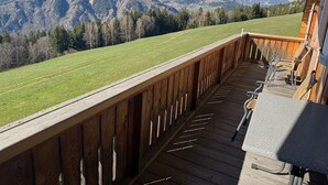 Una terraza de madera con vistas a un campo verde y montañas.