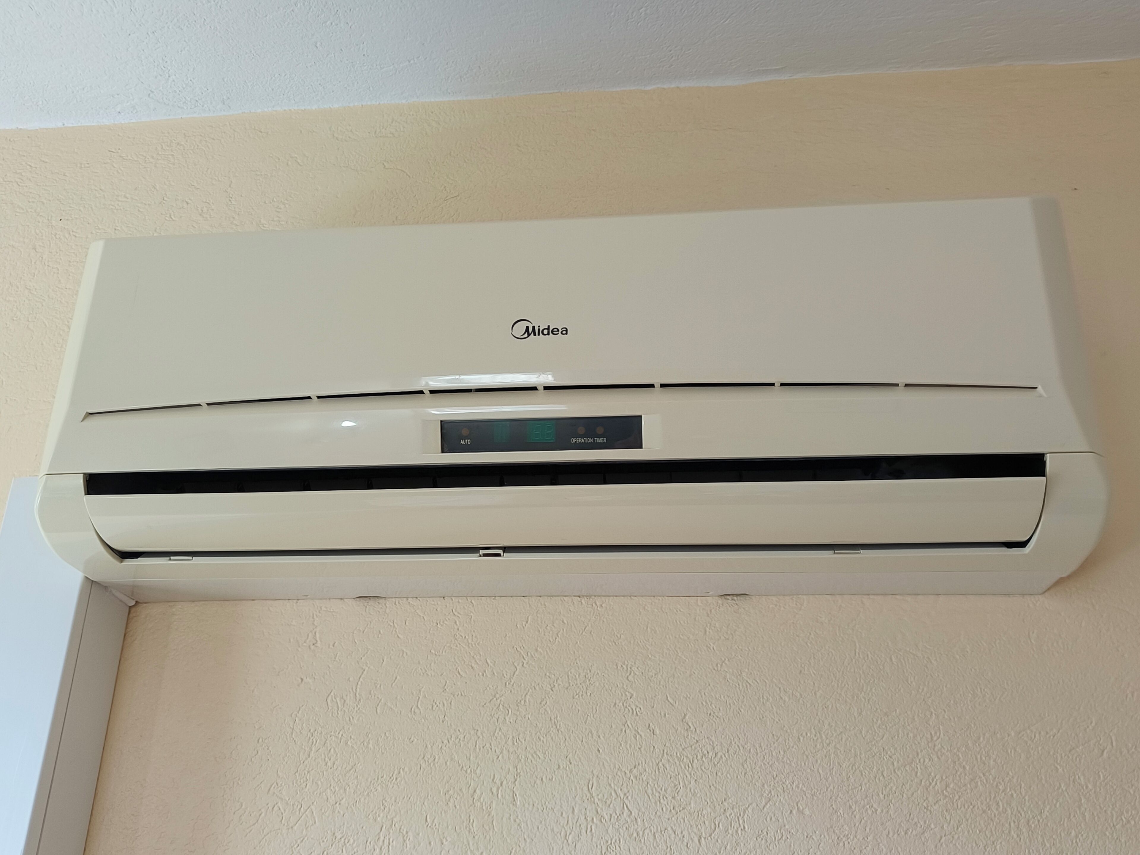 A white Midea air conditioner mounted on a beige wall.