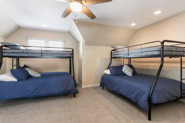 A room with two bunk beds, a ceiling fan, and a window.