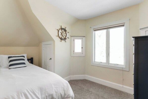 Un dormitorio con cama, ventana, puerta y un adorno en la pared.