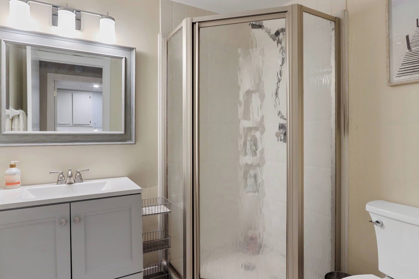 A bathroom with a shower, toilet, sink, and mirror.