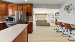 Una cocina moderna con armarios de madera, electrodomésticos de acero inoxidable y encimera blanca.