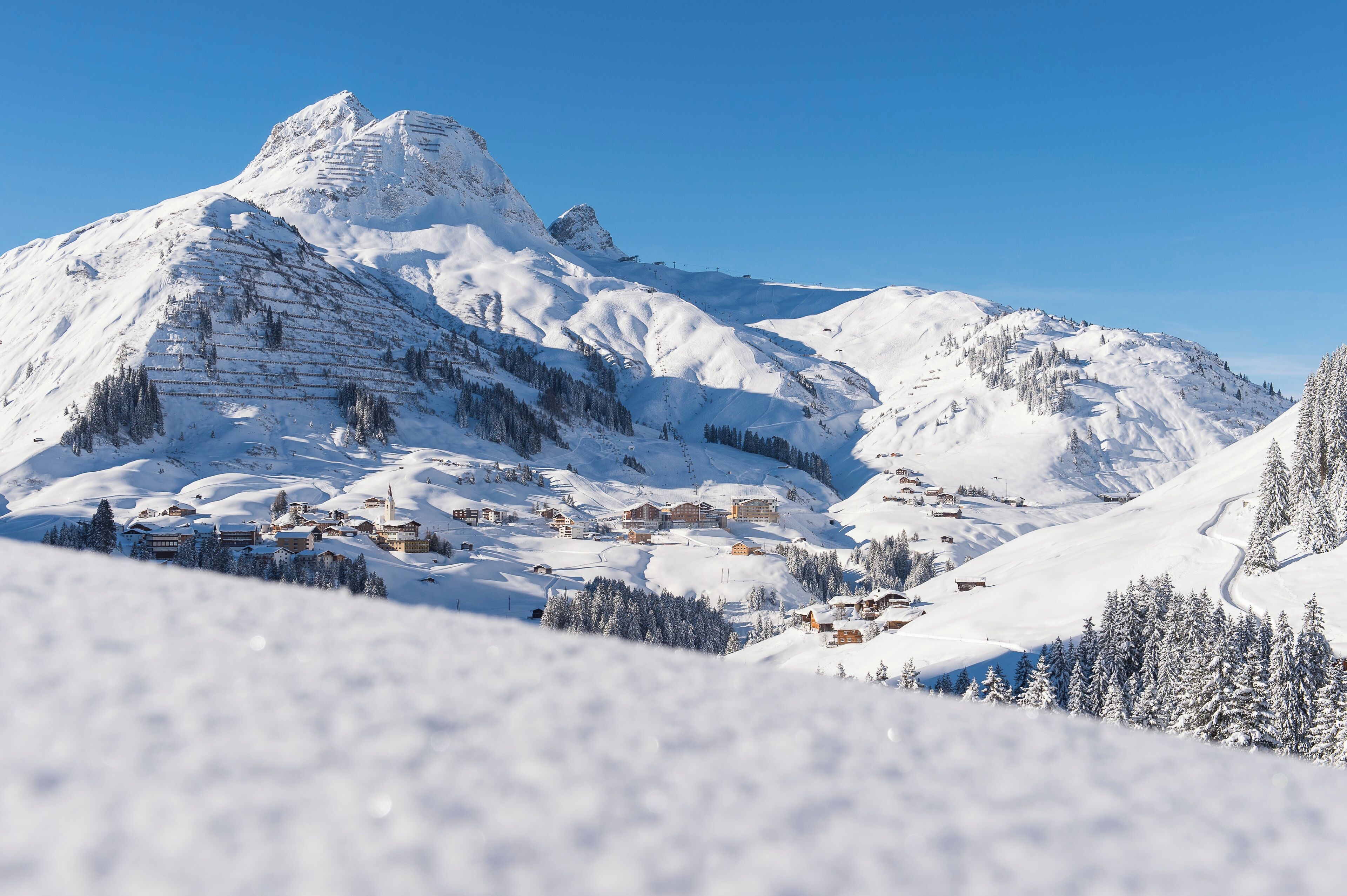A snow-covered mountain with a ski resort village nestled in the valley.