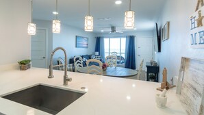 A modern kitchen with a central island, stainless steel sink, and pendant lighting.
