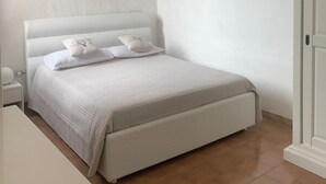 Una camera da letto con un letto, pareti bianche e una porta.