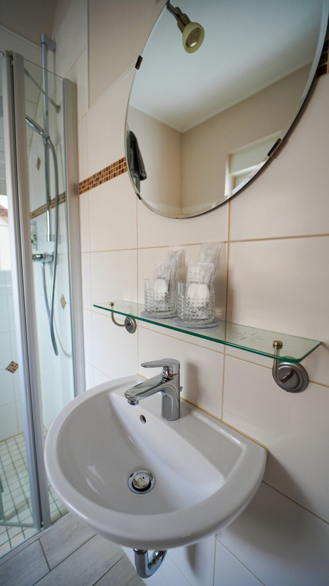 Un bagno con un lavandino in vetro, uno specchio e una doccia.