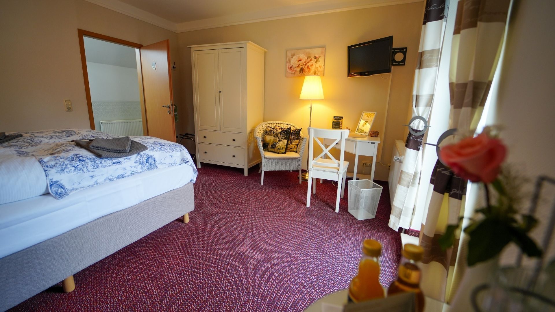A hotel room with a bed, a desk, a chair, a television, and a mirror.