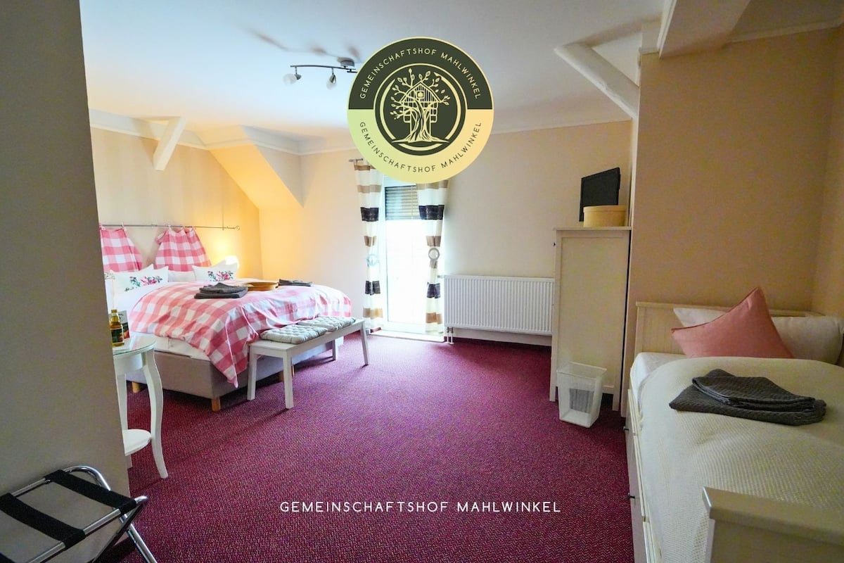 A hotel room with a bed, a desk, a chair, and a radiator.