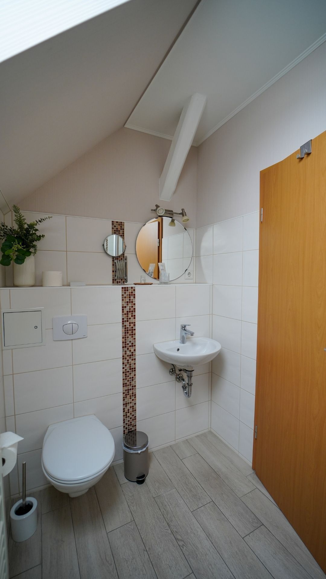 A small bathroom with a toilet, sink, and a mirror.