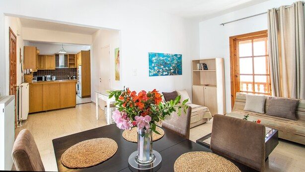 Una sala de estar moderna con una mesa de comedor, sofá y cocina al fondo.
