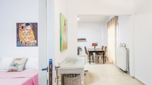 Una habitación moderna y bien iluminada con una cama, una mesa de comedor y sillas, y un radiador.
