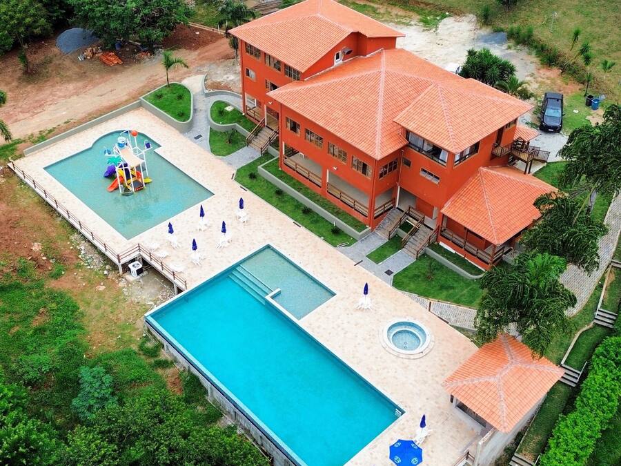 A large building with multiple swimming pools, a children's play area, and a well-maintained lawn.