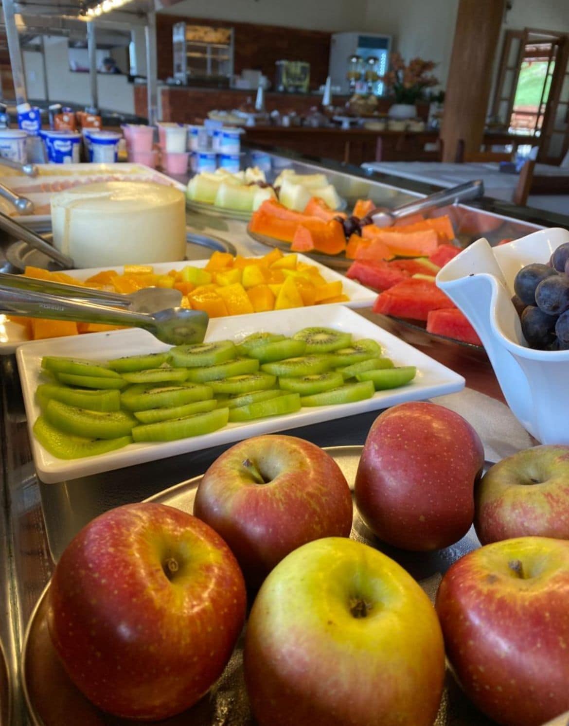 Un buffet proposant une variété de fruits et de légumes, notamment des pommes, des kiwis et des pastèques.