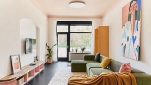 A modern living room with a sofa, a coffee table, a TV, and a large window. - Poets Place | Design Apartment in Kreuzberg (Berlin)